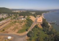 Aerial of land with trees next to river and roadway