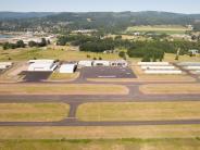Aerial of airport runway, hangar buildings, parked airplanes, trees and town in background