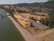 Aerial photo of beach, river, shipping dock, large sawdust pile, trees and houses in background