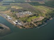 Aerial of river, shipping dock, industrial buildings and farmland in the background