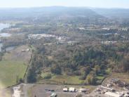 Aerial photo of river and land with trees and a few buildings in the distance