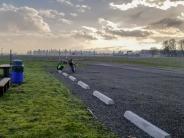 Picnic tables, man next to a motorcycle watching an airplane land