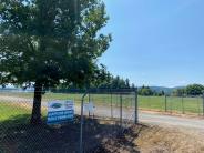 Sign for Scappoose Airport Public Viewing Area on fence, trees, open gate