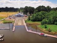 Boat ramp, docks, boats tied up to the dock, trees, building, sky