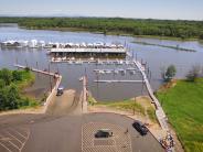 Boat ramp, docks, river, boats, kayaks being unloaded, trees, sky