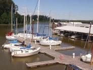 Sailboats moored at the marina docks, river, trees, sky