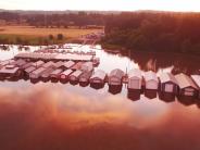 Boat houses, marina with boats tied up, boat launch, sunset, trees