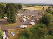 Aerial of campground with RVs, parking lot, trees, sky